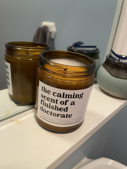 A candle labeled “the calming scent of a finished doctorate”