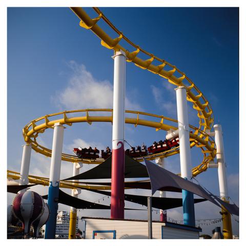 A rollercoaster train making a loop above a tent in the Santa Monica Pier.