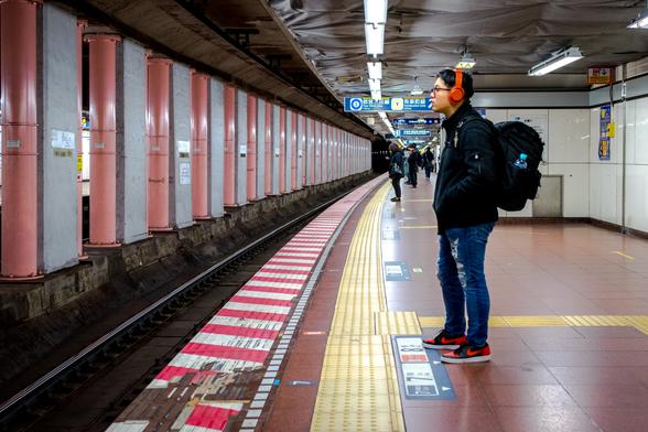 Home amb auriculars esperant el metro