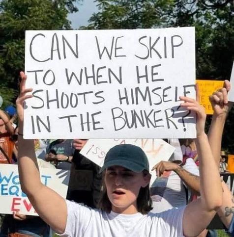 Photo of a young person holding up a demo poster.
"Can we skip to when he shoots himself in the bunker?"