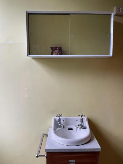 A small vintage sink with a mirror cabinet above it. You can see the top half of my head in the mirror