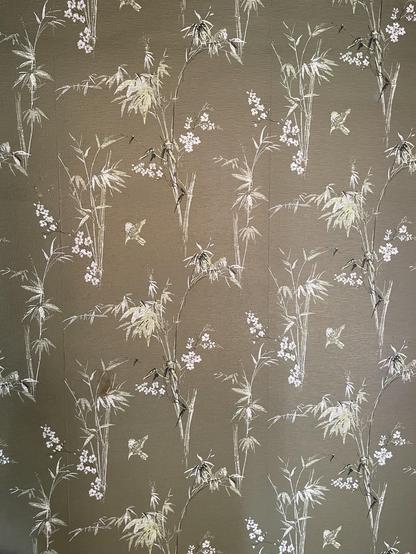 An olive green wallpaper. The pattern is white bamboo fronds.