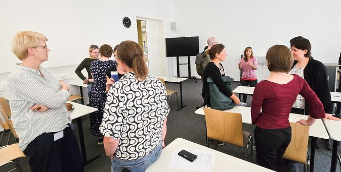 Personen auf der IBI-Schulung unterhalten sich im Seminar-Raum miteinander.