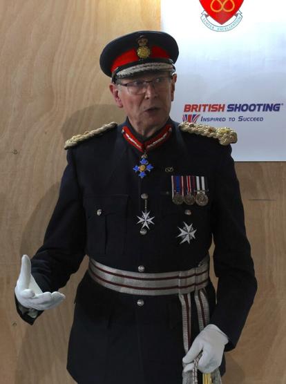 A uniformed man speaks to a crowd of people.