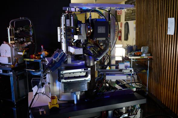 Photo of Zeiss Merlin electron microscope with a Zeiss Sigma electron microscope in the background. The column covers are removed, and there is some colored lighting.