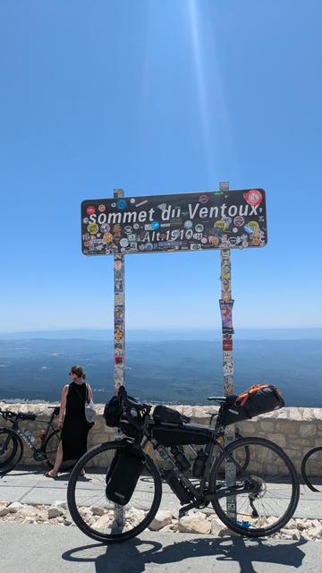Gravel bicycle with bikepacking gear next to a sign stating "sommet du Ventoux Alt. 1910m".
