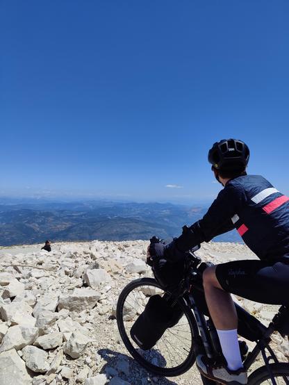 Cyclist near the summit of Mont Ventoux overlooking valleys and mountains to the north.