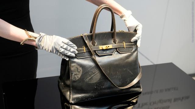 Eine Auktionsmitarbeiterin zeigt die Original-Birkin-Bag, die 1984 von Hermès für Jane Birkin entworfen wurde, vor der Versteigerung in Paris. (Foto: dpa Bildfunk, picture alliance/dpa/AP | Michel Euler)