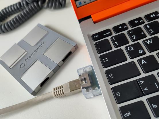Partial view of a framework laptop with an ethernet Module attached and some other modules in a 3d printed holder