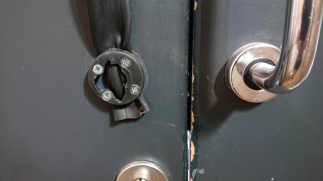 Close up of the bottom of a pair of pull handles on some doors.  

On the right is the shiny chrome of the proper handle.

On the left there's a black plastic disc with four screws holding it to the door.  The centre of the disc is a jagged hole where the handle has broken the plastic.  As a workaround, there's now a section of bike inner tube clamped between the disc and the door to fashion an alternative handle

We'll gloss over the chipped paintwork no the edge of the right-hand door, where an assortment of folk haven't been careful enough while carrying things through the doorway over the years.