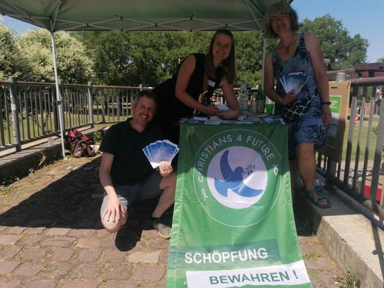 drei Menschen in der Sonne mit Christians for Future Flagge