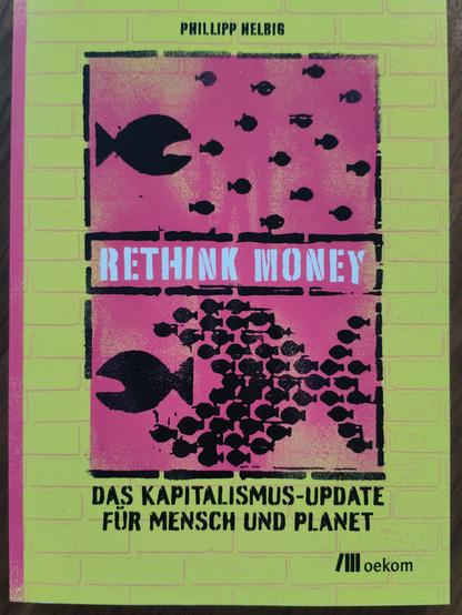 Buch von Phillipp Helbig.
Rethink Money. 
Gelber Rahmen mit großem Fisch der kleine Fische jagt in schwarz auf Pink. Unterbrochen vom Titel.
Darunter kleine Fische die großen Fisch jagen.