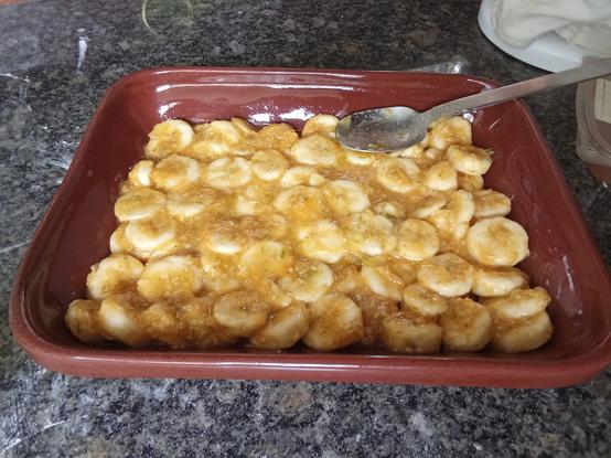 Cambures (en algunos lugares los llaman plátanos) cortados en rodajas y colocados en un molde rectangular (para hornear). Los cambures parecen caramelizados porque fueron revueltos con azúcar, harina de maiz, canela, ralladura de limón, ralladura de jengibre y jugo de limón antes de colocar en el molde. (Esta es la foto de lo que será el relleno del crumble).