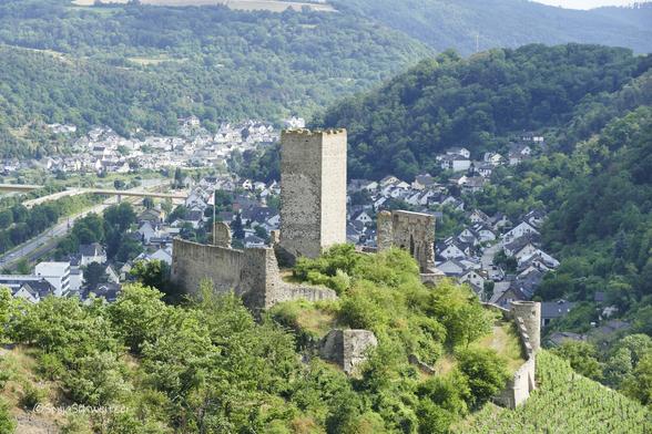 Der Blick geht auf den Bergfried der Burgruine, rechts der Burg fällt der Weinberg steil ab. Hinter der Burg geht der Blick auf die Häuser von Kobern/Gondorf und Niederfell sowie die Moselgoldbrücke.