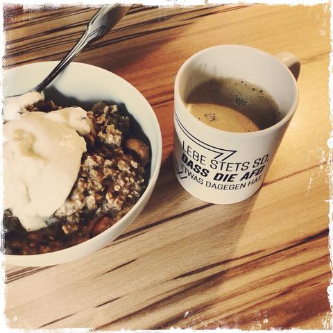 Ein quadratisches Foto im Retro-Stil. Zu sehen ist eine weiße Schale mit Apfel-Porridge, daneben ein weißer Kaffee-Becher mit der Aufschrift „Lebe stets so, dass die AfD etwas dagegen hat.“ // A square photo in retro style. You can see a white bowl with apple porridge, next to it a white coffee cup with the inscription "Always live in such a way that the AfD has something against it."