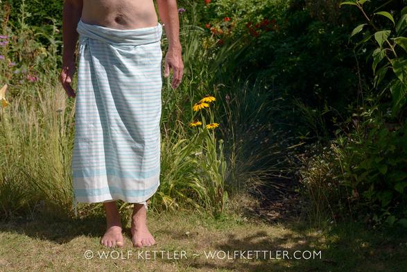Lower half of a man wearing a turquoise and white striped kikoi.