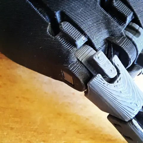 Gros plan sur une impression 3D en plusieurs parties noires et grises un peu complexe.