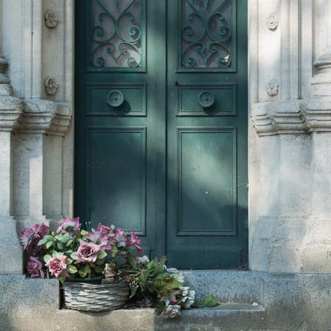 Photo of the door of a grave with flowers in front of it