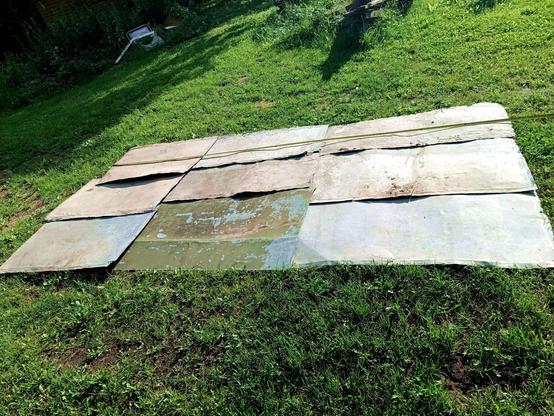 A bunch of used galvanized steel sheets laid out in the grass, forming a rectangle the exact size of a certain new firewood store. Some are dirty, several have folded over edges, one has peeling paint on it, all are a little bent.