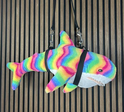 rainbow colored plush shark in a fancy carrying harness
