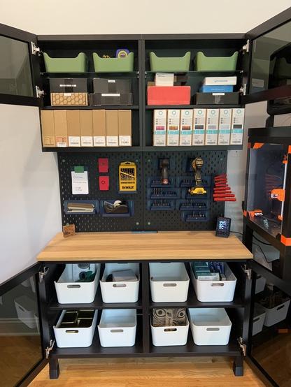 The same IKEA BESTÅ cabinets and SKÅDIS pegboards as before.  Now the glass doors are all open.  The bottom cabinets are full of IKEA UPPDATERA bins.  The top cabinets have smaller UPPDATERA bins on the top shelf and an assortment of cardboard boxes on the lower shelf.
