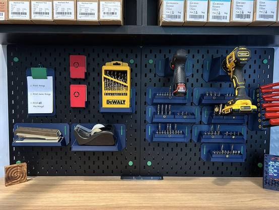 A close-up shows just the IKEA SKÅDIS pegboard.  It has all the attachments described in this thread plus a few more.  On the tabletop below there is a carved wooden block and a printed air quality meter.