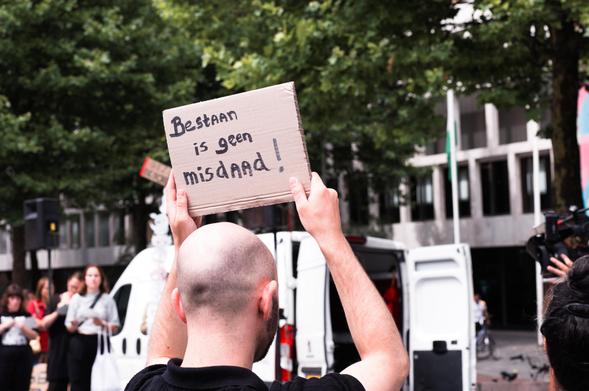 Protest bord - Bestaan is geen misdaad!