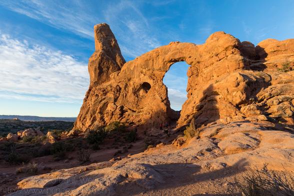 A big arch in the early morning light. You can just make out the people at its base
