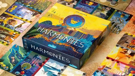 Een doos met het bordspel harmonies met een warme, kleurige getekende voorkant. Je ziet een soort leeuw met blauwe manen op gekleurde bergen met een gele hemellucht. Om de doos heen liggen gekleurde speelkaarten met allerlei getekende dieren.