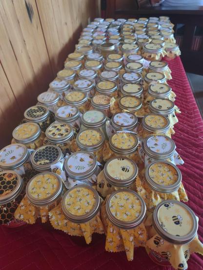 Rows & rows of jars of honey covering a small table.