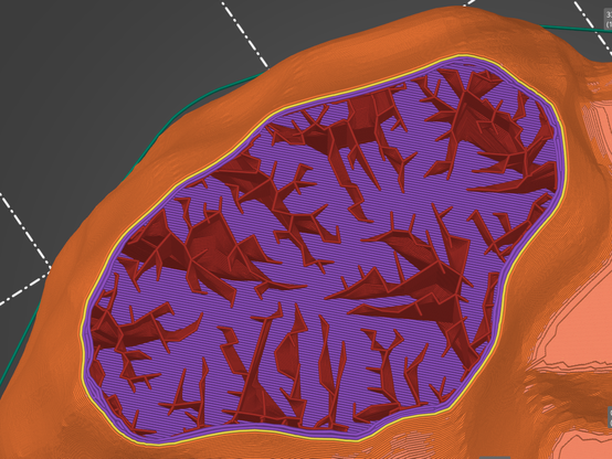Vu du haut de la pièce dans le logiciel Prusa Slicer. Ici on voit toujours en rouge la partie remplissage intérieur. Cette fois elle est plus dense parce qu'on est sur le haut de la pièce. Le remplissage est disposé sous forme de branches pointues qui font un peu penser à des éclairs.