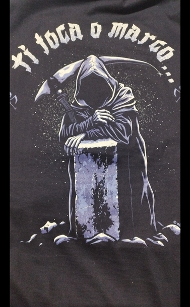 Foto de una camiseta negra, en la espalda hay un dibujo de un bloque de piedra grande, y apoyada en él, una figura que recuerda a la parca (la muerte con su capucha y la guadaña).

Hay una frase en gallego que dice: 

"Ti toca o marco..."

Que quiere decir: "Tú toca el marco..."