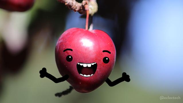 A photo of a deep red plum hanging from a tree with a blurred green and blue backdrop.I have scribbled a silly happy face and upturned arms on to the plum.