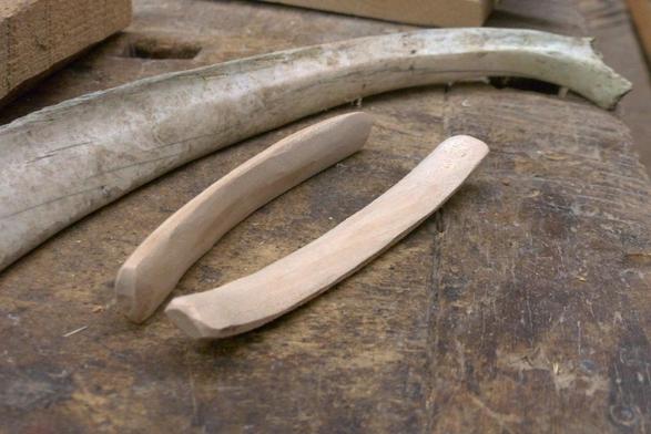Posés sur un établis, deux petit morceaux de bois taillés en forme de côtes et une vraie grande côte de vache, un peu usée et terreuse.