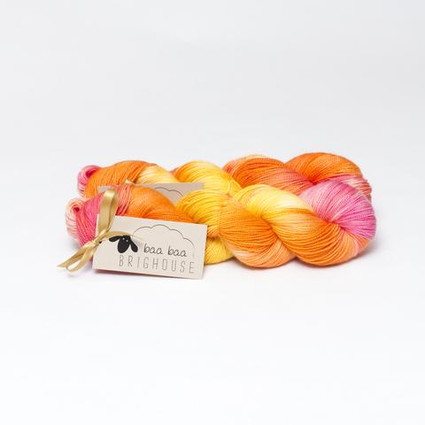 Picture shows two skeins ofyarn, one behind the other, in shades of orange, yellow and pink.