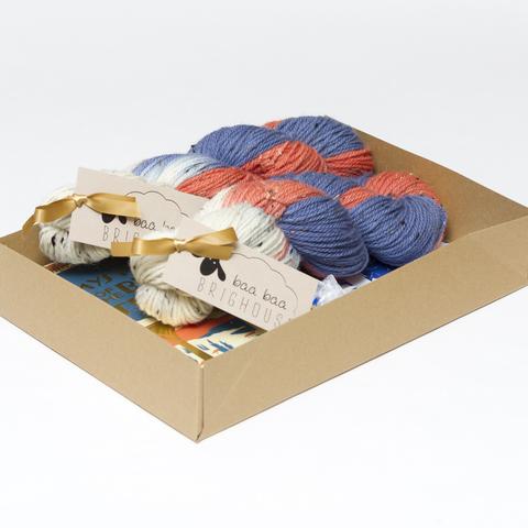 Picture shows an open A4 box containing two skeins of yarn in shades of blue, orange and white. The rest of the box contents is obscured by the sides of the box.