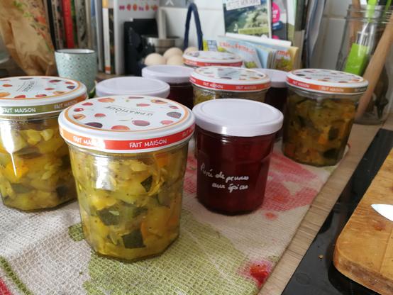 Des bocaux à couvercle à vis contenant des courgettes cuisinées pour certains et de la purée de prunes pour d'autres
