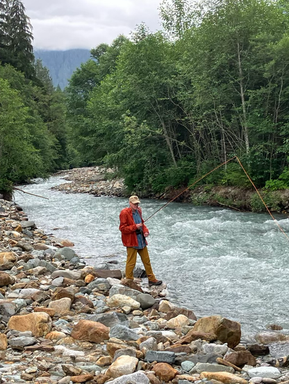 Guy in rain jacket holding a fly rod.