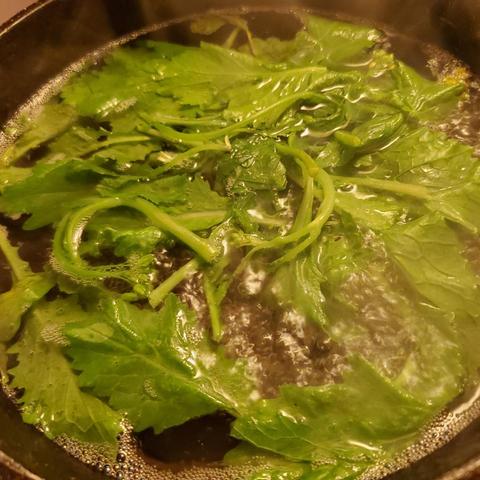 Chinese spinach & mustard greens being boiled in a wok with water.