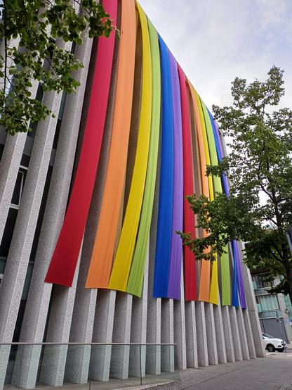 Foto: Fassade der Mex. Botschaft mit riesigen einzelnen Fahnen in Regenbogen-Farben.
