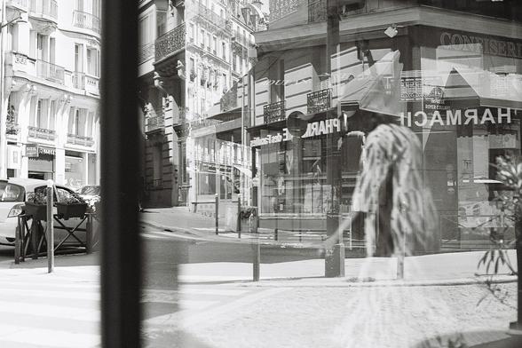 Reflections of a street scene in a window. Overlays of shop fronts, people, and cityscape.