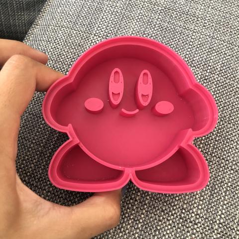 Emporte pièce en forme de Kirby de couleur rose tenu entre les doigts