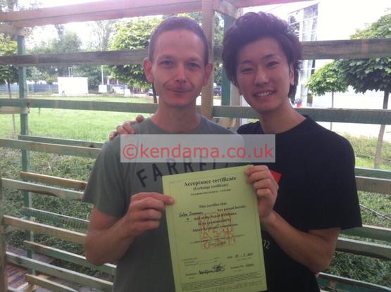 A happy kendama player displaying his new 4th Dan certificate, stood next to his examiner