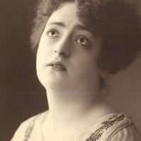 Retrato de Mimí Derba, actriz mexicana pionera del cine, con expresión pensativa y mirada directa hacia arriba, luciendo un vestido adornado con cuentas.