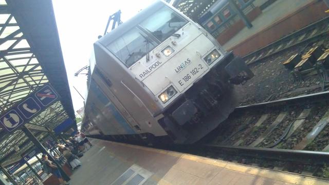 Locomotive pulls in alongside a railway station platform.