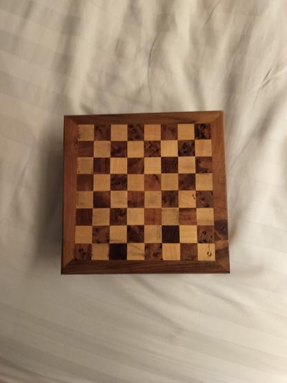 A small wooden chess board on a white surface
