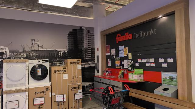 Eine Ecke im Fsmils Markt
Eine Pinnwand, Waren , Einkaufswagen etc. Eine Art Wimmelbild