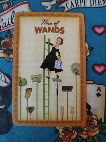 Card from the Housewives Tarot deck. 
Nine of Wands. 
A woman is climbing a ladder, almost to the top. She is surrounded by mops and brooms pointing up. She has a bucket and rag on the left hand.