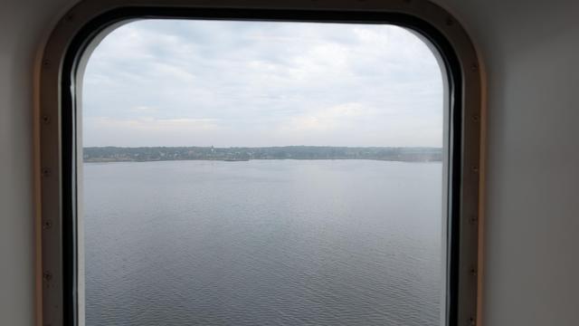 Picture taken from a ferry window. There is land on the horizon.
