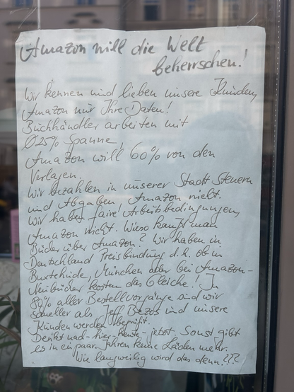 Handwritten note in the window of a bookstore about Amazon (text above)